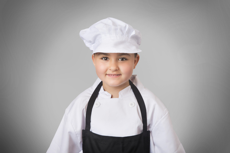 Portrait of a six years girl dressed like baker in grey backgroundの写真素材