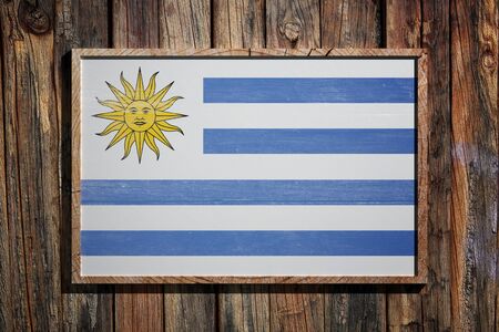 3d rendering of Uruguay flag on a wooden frame over a planks wallの写真素材
