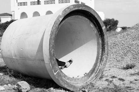 Woman hiding in a giant pipe in an open field in Tangier.の写真素材