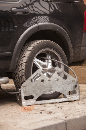 Wheel clamp on black car. Car has not been moved for days, violated the law.のeditorial素材