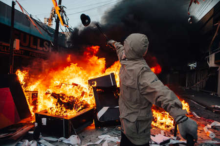 QUILPUE, CHILE - OCTOBER 20, 2019 - Protester throws on fire guard cap looted from a Bank during the...