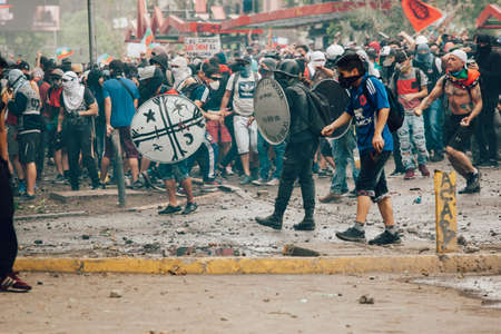 SANTIAGO, CHILE-NOVEMBER 8, 2019 - Protesters protect themselves from riot police with improvised shields during the protests against the government of Pinera, for the social crisis in the countryのeditorial素材