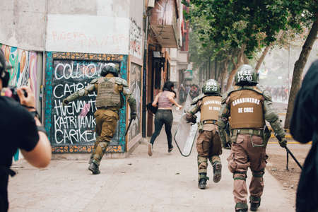 SANTIAGO, CHILE-NOVEMBER 8, 2019 - Girl runs away from the riot police during the protests against...
