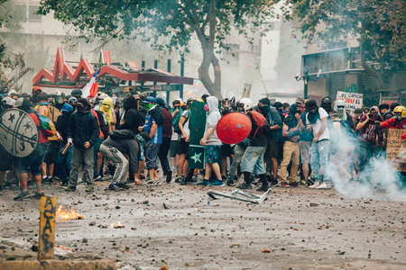 SANTIAGO, CHILE-NOVEMBER 8, 2019 - Protesters protect themselves from riot police with improvised shields during the protests against the government of Pinera, for the social crisis in the countryのeditorial素材