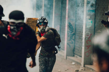 SANTIAGO, CHILE-NOVEMBER 8, 2019 - Protester runs away from tear bombs during the protests against the government of Sebastian Pinera, for the social crisis in the countryのeditorial素材
