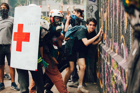 SANTIAGO, CHILE-NOVEMBER 8, 2019 - Red Cross volunteers use shields to protect civilians from police...