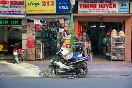 HO CHI MINH CITY, VIETNAM - MARCH 29: Man reading the newspaper while sitting on the motorbike on March 29, 2014 in Ho Chi Minh City, Vietnam.のeditorial素材