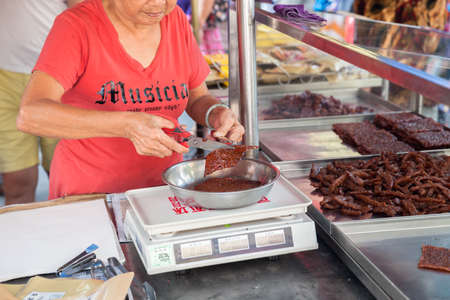 GEORGE TOWN, MALAYSIA - MARCH 23: Woman cut and weigh Chinese dried pork on March 23, 2016 on George Town, Malaysia.のeditorial素材