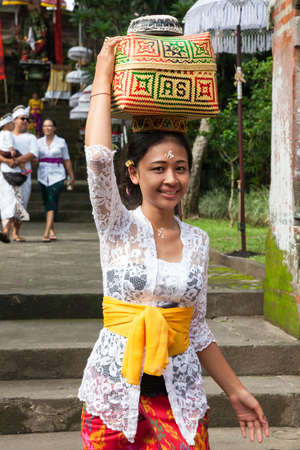 UBUD, INDONESIA - MARCH 2: Young woman with basket on the head during the celebration before Nyepi (Balinese Day of Silence) on March 2, 2016 in Ubud, Indonesia.のeditorial素材
