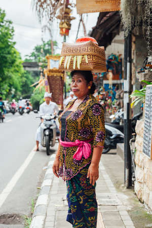 UBUD, INDONESIA - MARCH 2: Woman carrying basket on the head during the celebration before Nyepi (Balinese Day of Silence) on March 2, 2016 in Ubud, Indonesia.のeditorial素材