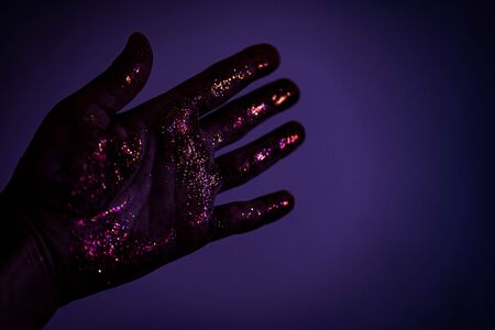 Crop shot from above of hand with palm covered in bright golden glittersの写真素材