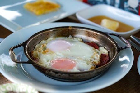 Fried egg in a old rustic frying pan, on an old wooden table. Countryside breakfast.
