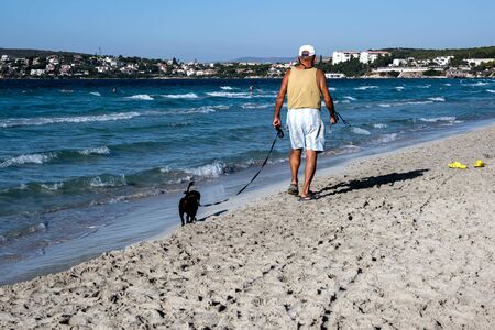 Senior man walking his dog at the beach. Cesme, Izmir, Turkey.