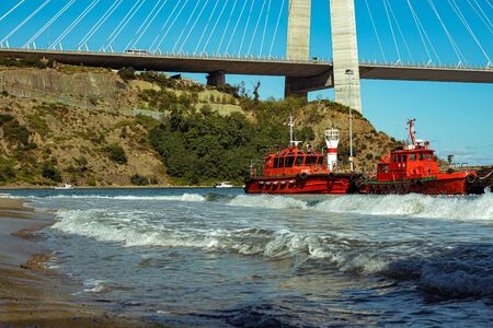 Red ships moored at the huge bridge background. Waived at the shore of the Black sea. Garipce village, Sariyer, Istanbul.の写真素材