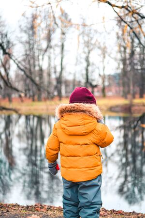 A little boy in winter cloths in late autumn or winter forest.の写真素材