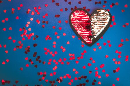 Red and silver heart of sequins on blue background. 14 February, Valentine's day concept.