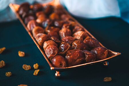 Beautiful bowl in Arabic style full of dry dates fruits symbolizing Ramadan on dark blue background.の写真素材