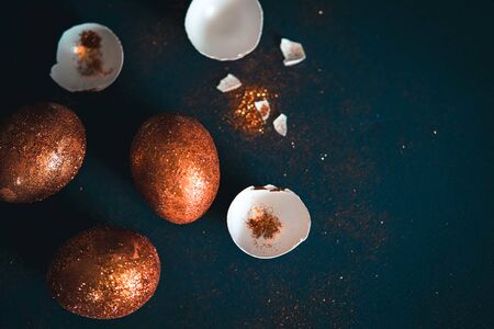 Golden or bronze decorated easter eggs on trendy black background.