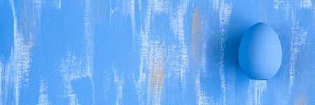 Light Blue Easter single egg on sky blue and gold canvas background. Minimalistic monochrome decoration concept. Perfect web banner.の写真素材