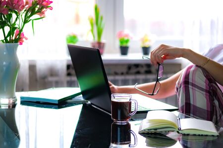 Cropped image of a girl or woman working on quarantine from home on the kitchen wearing pijama.Home...
