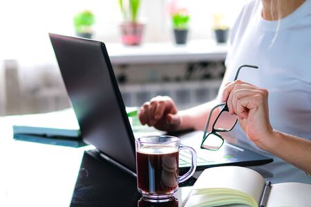 Cropped image of a girl or woman working on quarantine from home on the kitchen wearing pijama.Home...