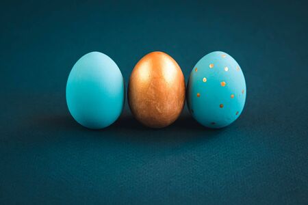 Easter set of gold and light blue eggs on blue background. Easter holiday decorations minimalistic concept.の写真素材