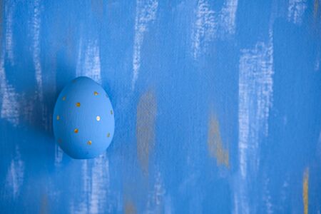 Light Blue Easter single egg on sky blue and gold canvas background. Minimalistic monochrome...