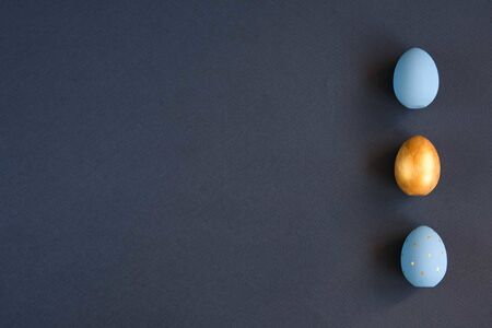 Easter set of gold and light blue eggs on blue background. Easter holiday decorations minimalistic...