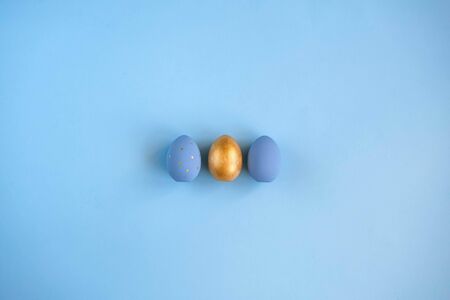 Easter set of gold and light blue eggs on blue background. Easter holiday decorations minimalistic...