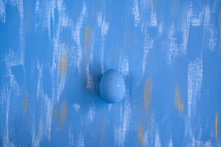Light Blue Easter single egg on sky blue and gold canvas background. Minimalistic monochrome decoration concept.の写真素材