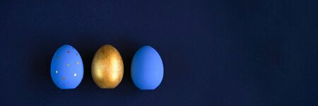 Easter set of gold and light blue eggs on blue background. Easter holiday decorations minimalistic concept. Web banner.の写真素材