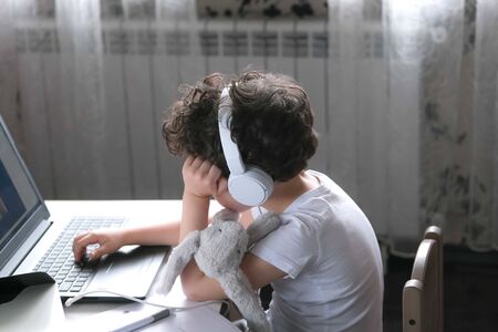 Tired Little boy with a toy doing his homework. Home schooling, pre-school, distance learning, social distancing, stay home concept.の写真素材