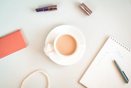 Morning planning with cup of coffee, notebook, smartphone and some feminine accessories. Modern woman's morning concept. Distant work and freelance or online shopping concept.の写真素材
