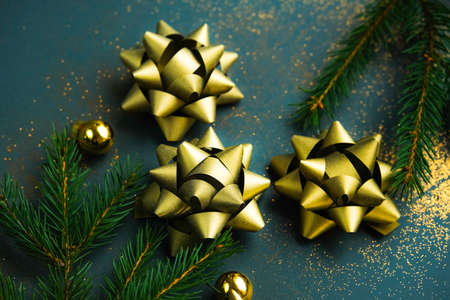 Christmas background. Tree gold ribbon bow knots for whrapping presents on dark green background.