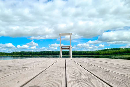 White wooden empty chair at the lake dock facing beautiful view.の写真素材