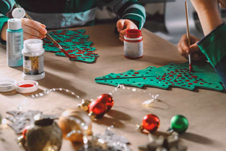 Two little kids making christmas decorations and postcards and painting wooden CHristmas trees.の写真素材