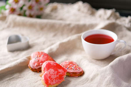 Heart shaped red hand made cookies and hibiscus tea in white cup and lights. Valentines day concept.の写真素材