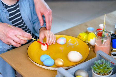 Little boy painting wooden eggs for Easter decoration. Candid image of kids crafting.の写真素材
