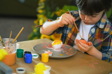 Little boy painting wooden eggs for Easter decoration. Candid image of kids crafting.の写真素材
