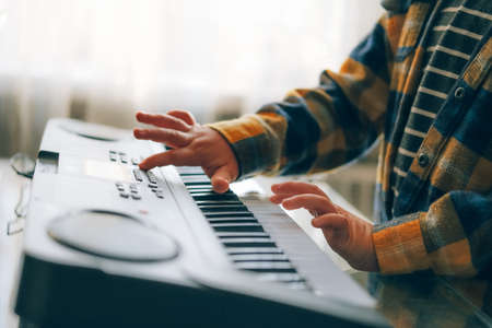 Close up of childs hands plying electric kids piano keyboard