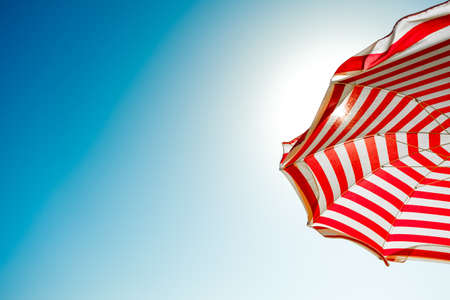 Red striped sun umbrella and blue sky.の写真素材