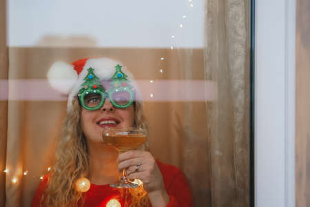 Woman in Santa hat and champane celebrating New Years Eve at homeの写真素材
