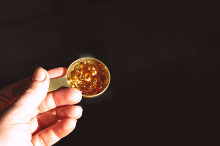 Yellow capsules of nutraceuticals in spoon. Pills and meds.の写真素材