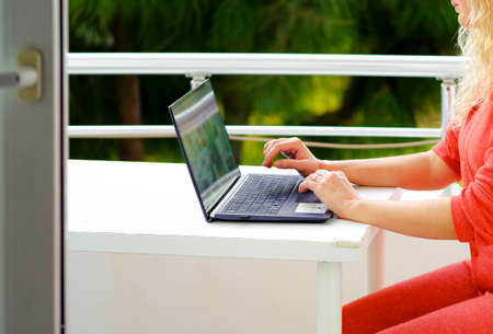 cropped image of woman working on her laptop computer in her pajamas on the balconyの写真素材