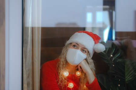 Happy woman in Santa hat and masquerade glasses with a glass of champane celebrating New Year's Eveの写真素材