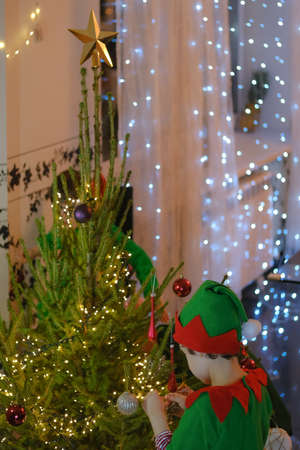Little kids wearing masquerade costumes and elf hat decorating Christmas tree at home