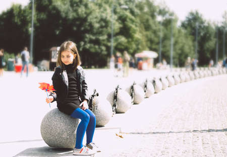 Happy girl with red pinwheel walking outdoors.の写真素材