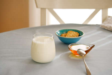 Glass of milk, honey and whole wheat cookies on the table.の写真素材