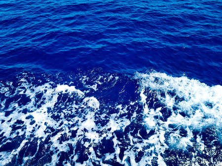 Deep blue surface of transparent sea water with sun glints