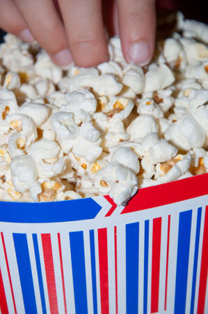 woman's hand picking popcorn bowlの写真素材